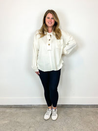 Wearing cream quarter button sweater.